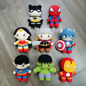 May include: A collection of eight crocheted superhero characters, including Batman, Superman, Wonder Woman, Thor, Captain America, Hulk, Iron Man, and Spiderman. Each character is approximately 6 inches tall and features detailed stitching and colorful accents.