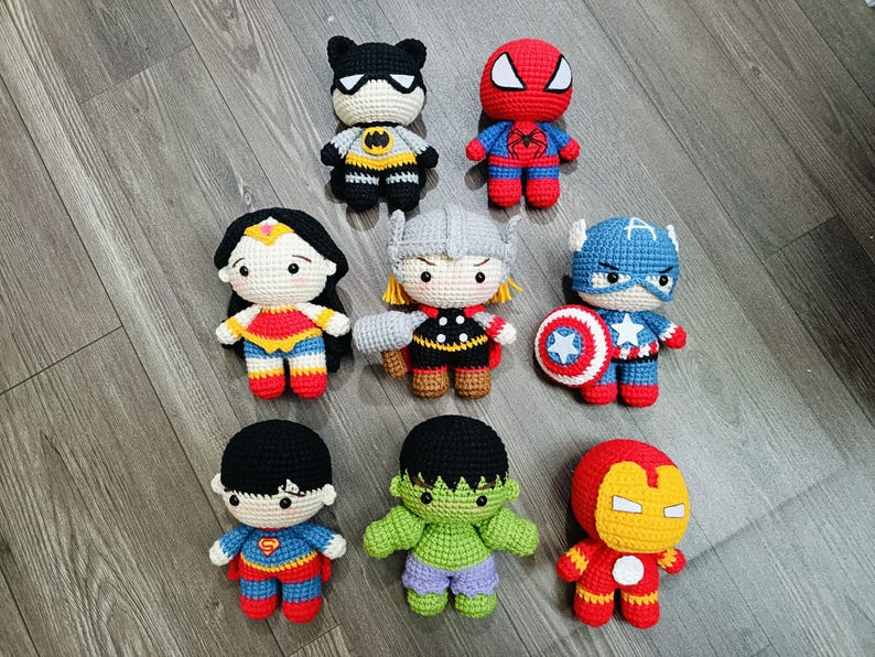 May include: A collection of eight crocheted superhero characters, including Batman, Superman, Wonder Woman, Thor, Captain America, Hulk, Iron Man, and Spiderman. Each character is approximately 6 inches tall and features detailed stitching and colorful accents.