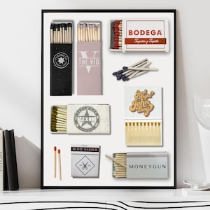 May include: A framed print featuring various matchbox designs. The matchboxes display text such as "BODEGA", "THE VIG", and "MONEYGUN". The color palette includes black, white, red, and gold, with a minimalist aesthetic.