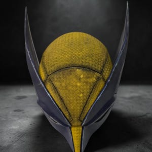 Puede incluir: Una m&aacute;scara inspirada en Wolverine, con una superficie texturizada amarilla y detalles en azul oscuro. La m&aacute;scara tiene orejas puntiagudas y un dise&ntilde;o afilado y angular, sobre un fondo oscuro.