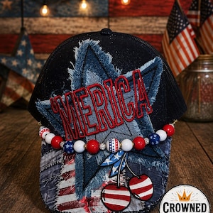 May include: A black trucker hat with a denim star and the word "MERICA" in red embroidery. The hat features a beaded accent with red, white, and blue beads, and cherry patches. The hat is decorated with patriotic themes.