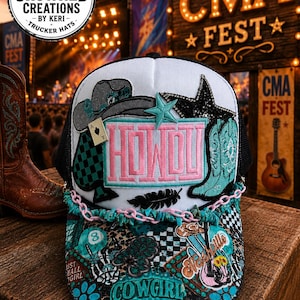 Pode incluir: Um boné de caminhoneiro com parte superior branca e costas de malha preta, com um design "HOWDY" com chapéu de cowboy, botas e enfeites de estrela. A aba tem um design de patchwork colorido com a palavra "COWGIRL".