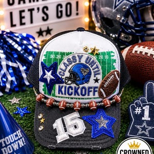 Puede incluir: Una gorra trucker negra y blanca con un gráfico de campo de fútbol, un casco azul y el texto "CLASSY UNTIL KICKOFF". La gorra está adornada con un borde de cuentas en forma de balón, un parche plateado del número "15" y estrellas azules.
