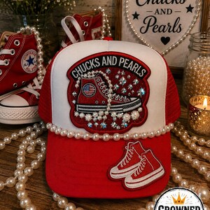 May include: A red and white trucker hat featuring a central patch with the text CHUCKS AND PEARLS, a red high-top sneaker graphic, and pearl embellishments. The brim displays a smaller red sneaker patch, and a string of pearls lines the base.