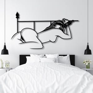 Könnte beinhalten: Schwarz-weiße Silhouette einer Person, die auf einem Bettrahmen liegt. Die Person trägt eine Augenbinde und hat die Arme über dem Kopf erhoben.