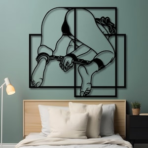 Könnte beinhalten: Schwarze Wandkunst aus Metall, die eine stilisierte Figur in gebundener Pose darstellt. Die Figur ist mit gekreuzten Beinen und gebundenen Händen dargestellt. Die Kunst besteht aus mehreren geometrischen Formen.
