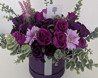 Könnte beinhalten: Ein violetter Blumenstrauß in einer violetten Box mit einem weißen Band. Der Strauß enthält violette Rosen, Lavendel und Eukalyptus.