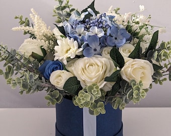 Könnte beinhalten: Ein blauer und weißer Blumenstrauß in einer blauen Box. Der Strauß enthält weiße Rosen, blaue Hortensien und weißen Schleierkraut.