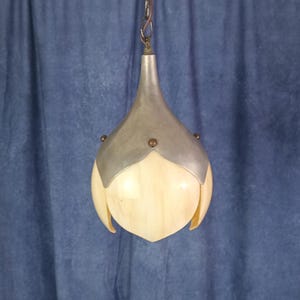 May include: A hanging pendant light fixture featuring a cream-colored, petal-shaped glass shade encased in a brushed silver metal cap. The metal top is secured with small, dark circular rivets and connects to a metal chain for ceiling suspension.