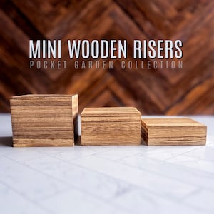 Puede incluir: Tres elevadores de madera de diferentes tama&ntilde;os, hechos de madera marr&oacute;n claro con un patr&oacute;n de veta natural. Los elevadores est&aacute;n dispuestos en una fila del m&aacute;s grande al m&aacute;s peque&ntilde;o, con el elevador m&aacute;s grande a la izquierda y el m&aacute;s peque&ntilde;o a la derecha. Los elevadores est&aacute;n sobre una superficie blanca. MINI WOODEN RISERS POCKET GARDEN COLLECTION