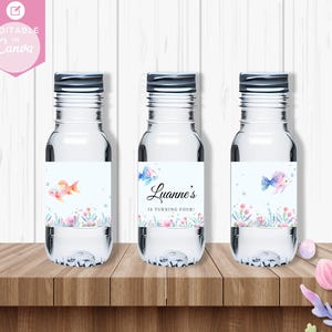 May include: Three clear water bottles with labels featuring a watercolor design of fish and bubbles. The labels also include the text "Luanne's is turning four!"