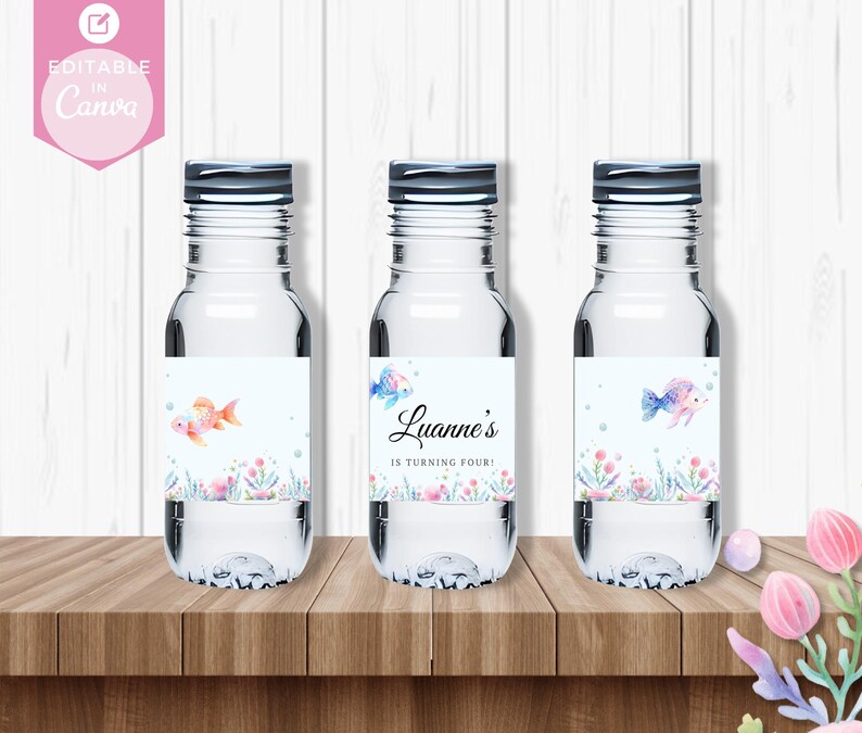 May include: Three clear water bottles with labels featuring a watercolor design of fish and bubbles. The labels also include the text "Luanne's is turning four!"