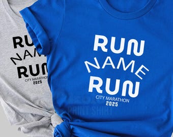 Może przedstawiać: Dwie koszulki, jedna szara i jedna niebieska, z białym napisem "RUN NAME RUN". Tekst jest ułożony w stosie, pod kątem. Poniżej tekstu znajduje się "CITY MARATHON 2025". Niebieska koszulka jest zawiązana na dole.