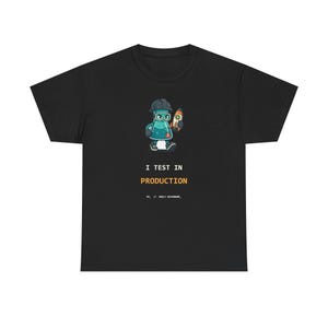 May include: A black short-sleeve t-shirt featuring a cartoon graphic of a teal laboratory flask wearing a hard hat and goggles while holding a small rocket. Below the graphic, the text reads I TEST IN PRODUCTION in white and orange letters.