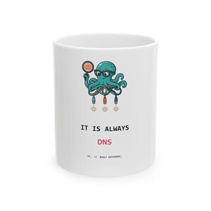 Peut inclure: Un mug en céramique blanc orné d'une pieuvre sarcelle portant des lunettes noires, tenant une loupe sur une icône de globe et reliée à trois câbles Ethernet. Sous le graphique, le texte indique IT IS ALWAYS DNS et FP_ // BUILT DIFFERENT_.