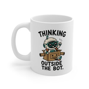 May include: A white ceramic mug featuring a graphic of a small robot wearing teal glasses, sitting inside a brown cardboard box. The text above and below the robot reads, "THINKING OUTSIDE THE BOT." The design uses black, teal, and orange colours.