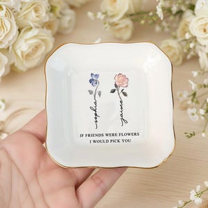 May include: A white ceramic trinket dish with a gold rim, featuring floral illustrations and the names "Sophia" and "Jaime." The dish includes the text "IF FRIENDS WERE FLOWERS I WOULD PICK YOU."