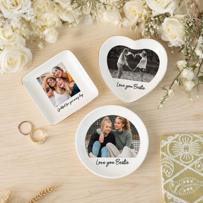 Peut inclure: Trois petits plats &agrave; bijoux en c&eacute;ramique blanche avec des bords dor&eacute;s, chacun avec une photo. L'un est carr&eacute;, l'autre en forme de c&oelig;ur et l'autre rond. Le plat carr&eacute; porte l'inscription "Grateful for you every day". Les plats en forme de c&oelig;ur et ronds portent l'inscription "Love you Bestie."