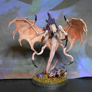 May include: A painted miniature creature featuring a pale, segmented body with a dark purple head crest and large, expansive wings with pinkish-tan membranes. The figure has sharp black claws and stands on a textured, circular base with debris.