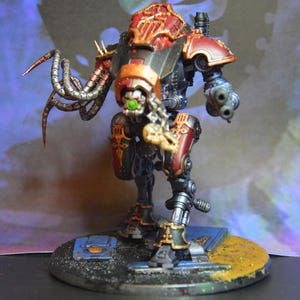 May include: A red and black painted robot with a green eye and a long, segmented arm with claws. The robot is standing on a circular base with a gray and brown surface.
