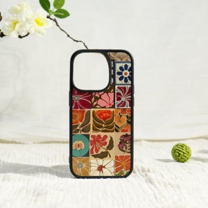 May include: Black phone case with a floral patchwork design. The case features a black border and a series of colorful squares, each displaying a different flower pattern in shades of red, orange, pink, and blue. The case is set against a white background.