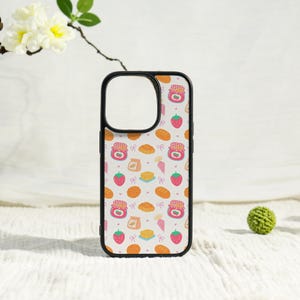 May include: A black phone case featuring a repeating pattern of breakfast items including red strawberry jam jars with checkered lids, fresh strawberries, golden brown bread loaves, butter squares, and small pink bows on a light background.