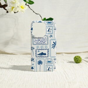 May include: White phone case with a blue pattern of stamps featuring sailboats, palm trees, and crabs. The case has a cutout for the camera and buttons. The design is repeated across the entire surface of the case.