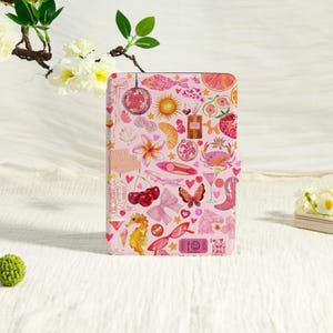 May include: A rectangular e-reader case featuring a light pink background covered in a collage of colourful illustrations including a disco ball, sun, cherries, seahorse, butterfly, crab, cowboy boots, sunglasses, and a ticket with a smiley face.