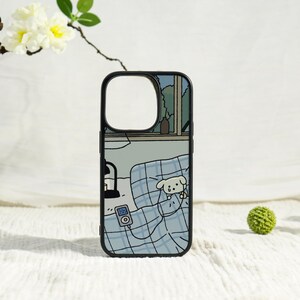 May include: Black phone case featuring a cartoon illustration of a dog in bed. The design includes a window, lamp, and music player. The case has a black border and a cutout for the camera.