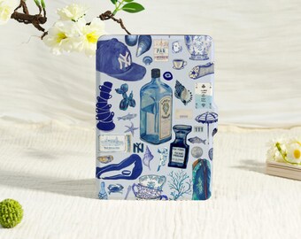 May include: A rectangular e-reader case featuring a collage of blue and white illustrations, including a baseball cap, a gin bottle, a perfume bottle, seashells, a stack of teacups, a beach umbrella, and various small objects on a light background.