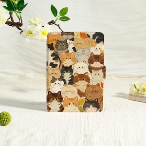 May include: A rectangular case featuring a repeating pattern of cartoon cats in various colors, including orange, brown, gray, and black. The cats have different expressions and markings. The case has a magnetic closure.