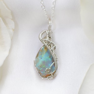 Peut inclure: Un collier en argent avec un pendentif en opale en forme de larme enveloppé de fil d'argent.