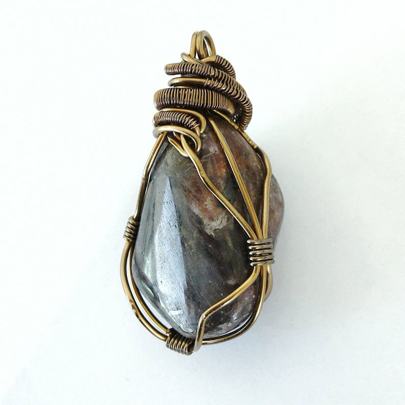 May include: A handcrafted pendant featuring a polished, teardrop-shaped stone with a mix of gray, brown, and reddish hues. The stone is intricately wrapped in bronze-colored wire, creating a unique and artistic jewelry piece.