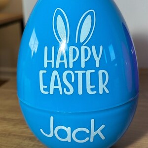 May include: A blue plastic Easter egg with bunny ears and the text "Happy Easter" and "Jack" in white.