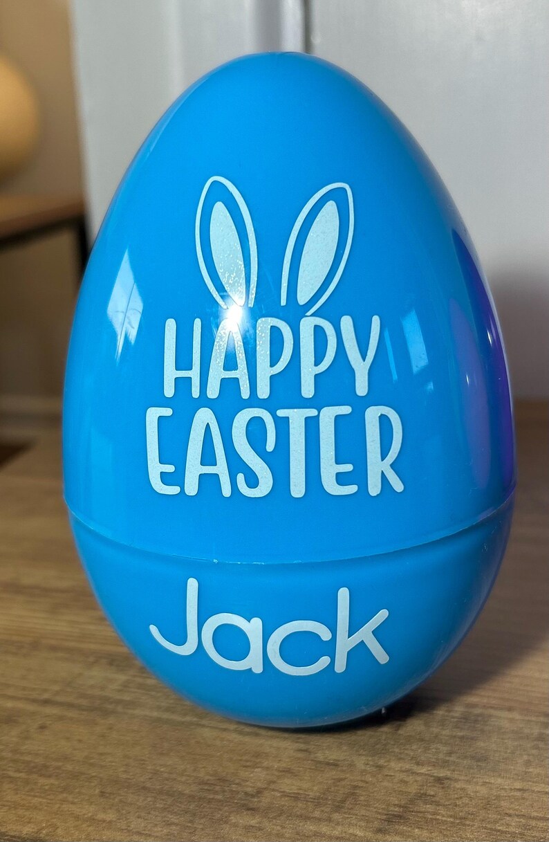 May include: A blue plastic Easter egg with bunny ears and the text "Happy Easter" and "Jack" in white.