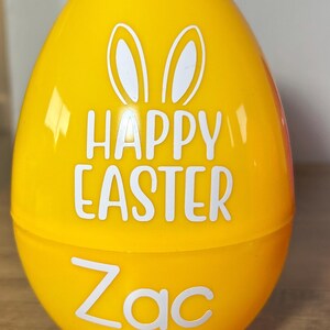 May include: A yellow plastic Easter egg with white bunny ears and the text "Happy Easter Zac".