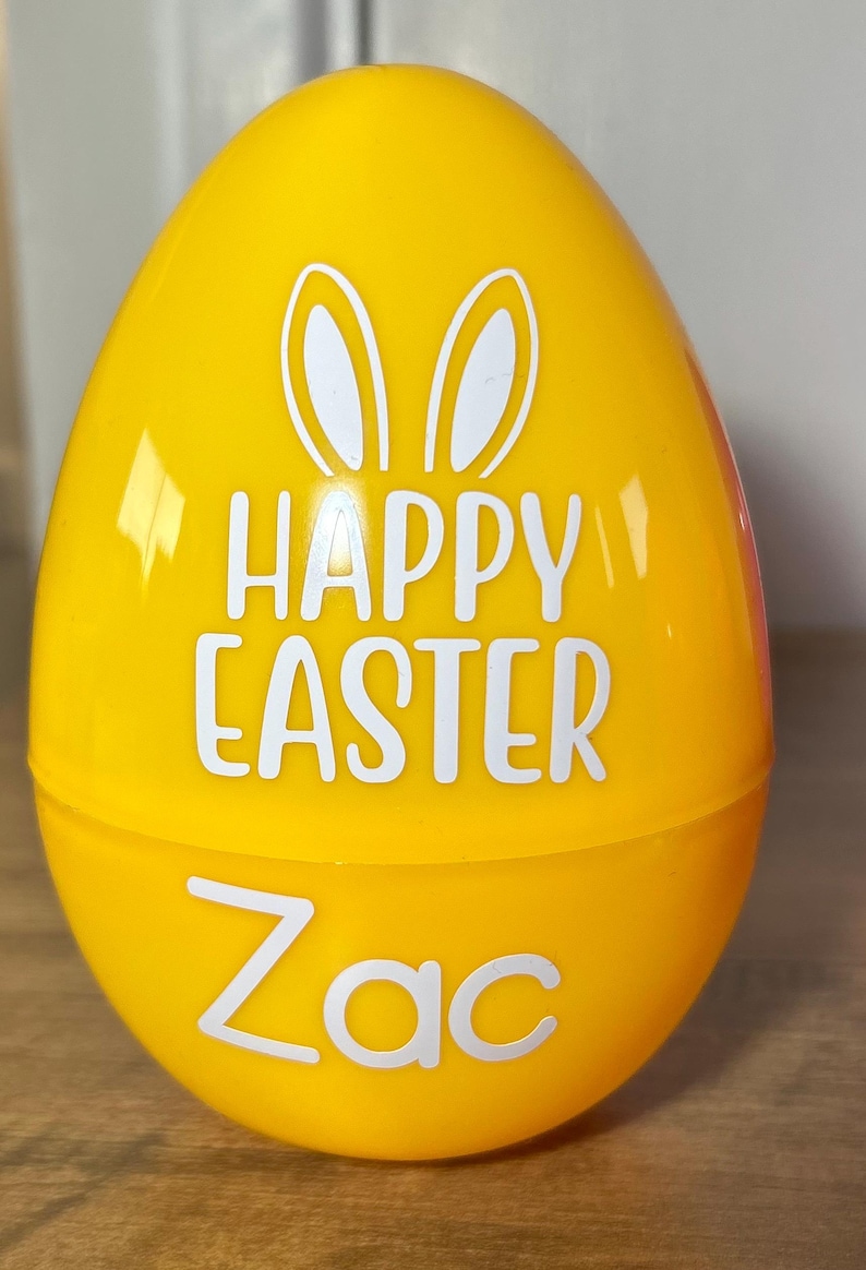 May include: A yellow plastic Easter egg with white bunny ears and the text "Happy Easter Zac".
