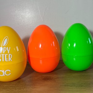 May include: Three plastic Easter eggs, one yellow with the text "Happy Easter Zac", one orange, and one green.