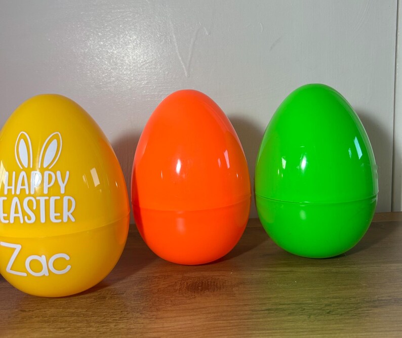 May include: Three plastic Easter eggs, one yellow with the text "Happy Easter Zac", one orange, and one green.