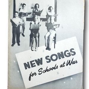 以下が含まれることがあります： 「NEW SONGS for Schools at War」と題された白黒の書籍カバー。子供たちが歌っている写真が特徴で、背景は教室です。カバーは、星のアクセントが付いた明るい灰色の背景です。