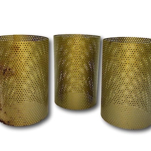 May include: Three cylindrical, gold-colored metal candle holders. Each holder is perforated with small, evenly spaced holes. The holders have a slightly aged appearance, with some showing signs of wear.