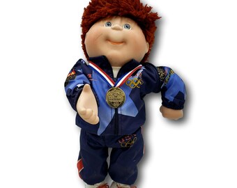 Bambola mascotte della squadra olimpica USA dei Cabbage Patch Kids OlympiKids 1996 con medaglia, tenuta da campione, espositore