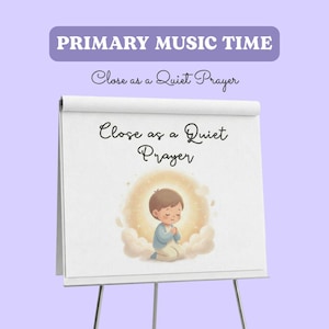 May include: A white flip chart on a stand featuring the text PRIMARY MUSIC TIME and Close as a Quiet Prayer. Below the text is an illustration of a child with brown hair kneeling with hands clasped in prayer, surrounded by a soft glowing light.