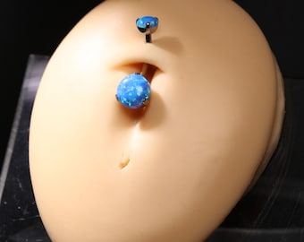 May include: A belly button ring set with a blue opal-like stone. The jewelry is set in a dark metal and is displayed on a tan-colored mannequin. The top piece is a small stud, and the bottom piece is a larger, round stone.