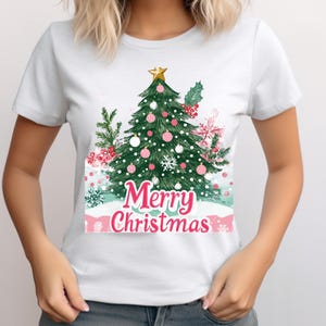 May include: White t-shirt featuring a green Christmas tree illustration and the text "Merry Christmas" in pink.
