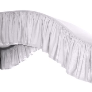 May include: White bed skirt with a ruffled edge. The skirt is made of a soft, lightweight fabric and is perfect for adding a touch of elegance to any bedroom.