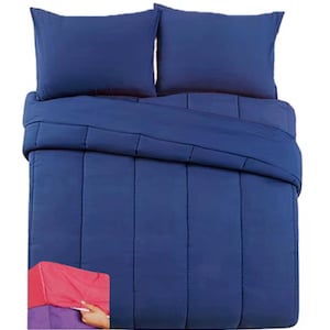 May include: A solid navy blue comforter set featuring a quilted design with vertical stitching lines. The set includes two matching rectangular pillow shams and a comforter. A small inset shows a pink fitted sheet being placed on a mattress corner.