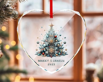 May include: Heart-shaped Christmas ornament with a festive tree design. The ornament features a red ribbon for hanging and the text "Marry & Charlie 2025". The tree is decorated with ornaments and stars.