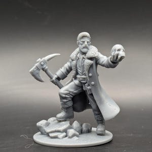 May include: A gray 3D printed miniature of a person wearing a long coat, holding a skull in one hand and a pickaxe in the other. The miniature is standing on a rocky base.