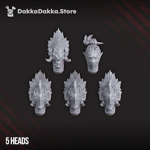 May include: Five gray, detailed miniature heads with elaborate headdresses and masks. One head has a skull face, another has a mask, and the others have a similar design. The text "5 HEADS" is at the bottom, and the DakkaDakka.Store logo is at the top.